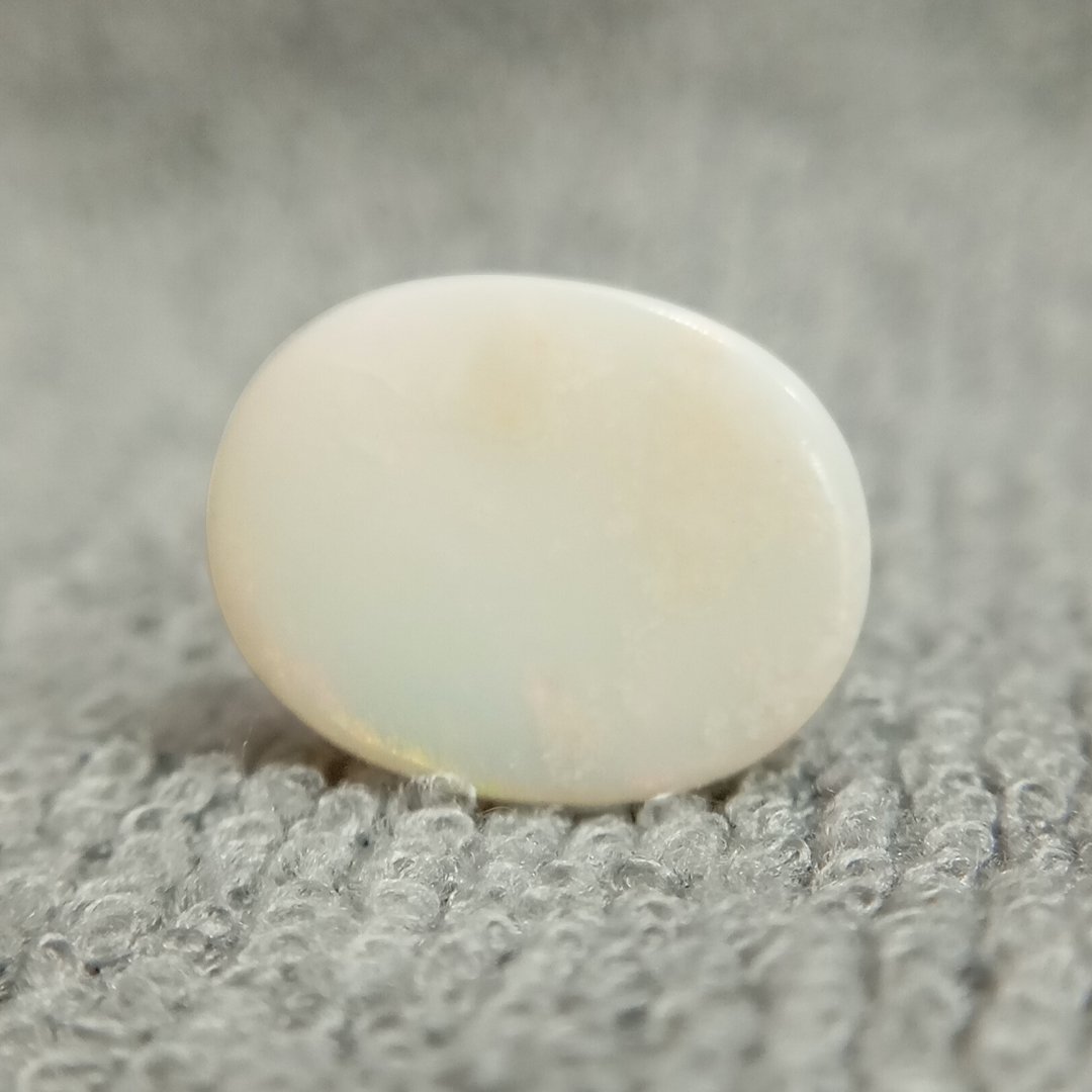 A close-up of a Natural Opal gemstone displaying a mesmerizing play of colors with iridescent flashes.
