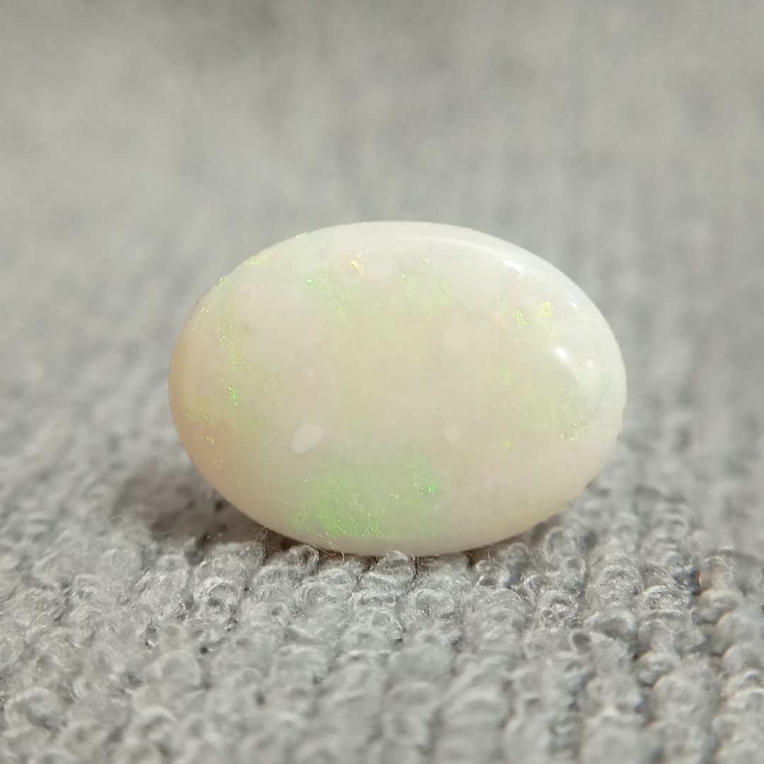 A close-up of a Natural Opal gemstone displaying a mesmerizing play of colors with iridescent flashes.